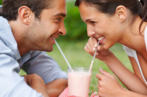 Two people who do not suffer from sensitive teeth sharing a strawberry milkshake.