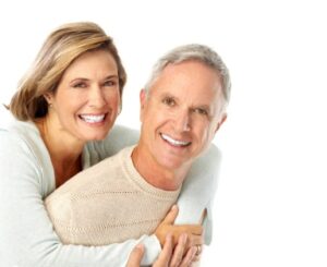 A smiling older couple stands together, posing happily for the camera, radiating warmth and joy.