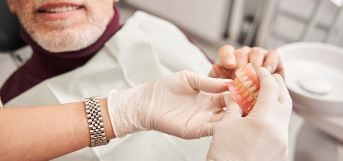 doctor showing a pair of dentures to a patient